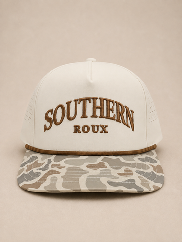 Cream five-panel Southern Roux rope cap with arched embroidery and marsh-camo brim.