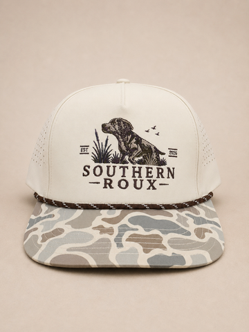 Cream five-panel Southern Roux rope cap with dog-and-marsh logo and marsh-camo brim.
