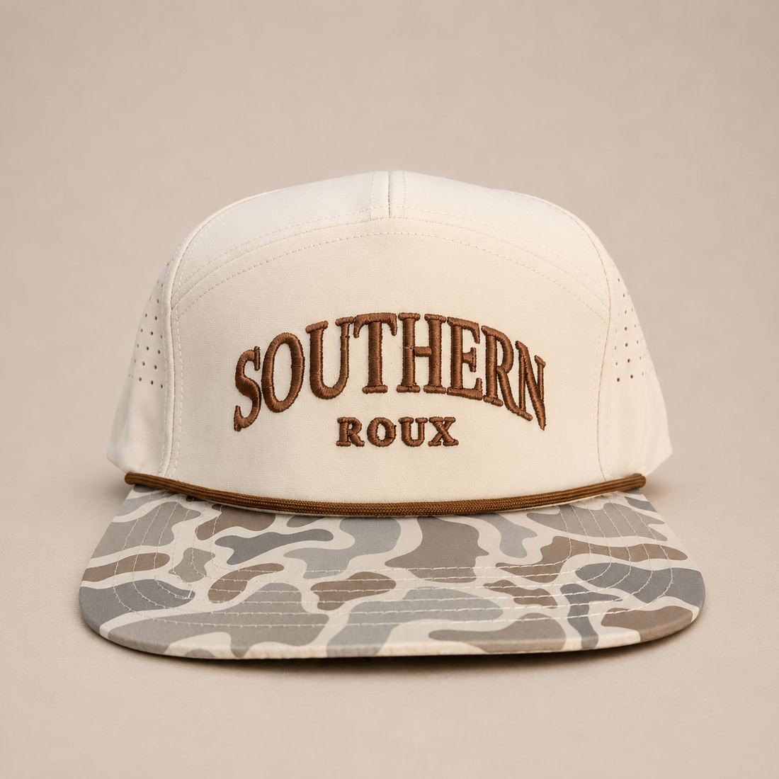 Cream seven-panel Southern Roux rope cap with arched embroidery and marsh-camo brim.